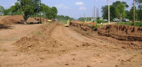 A construction site with a lot of dirt and trees in the background