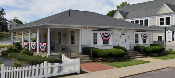 A white building with a porch, decorated with red, white, and blue bunting.