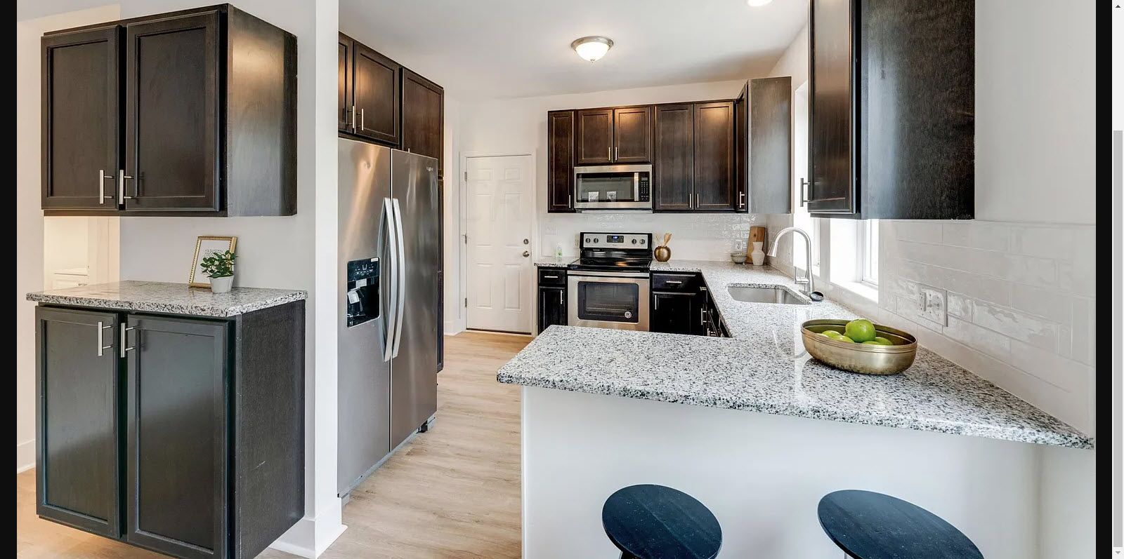 A kitchen with black cabinets , granite counter tops , and stainless steel appliances.