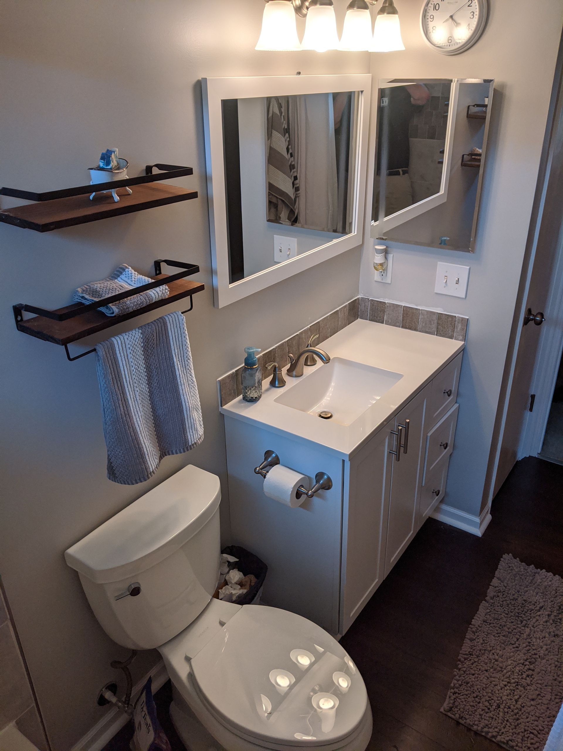 A bathroom with a toilet , sink and mirror.