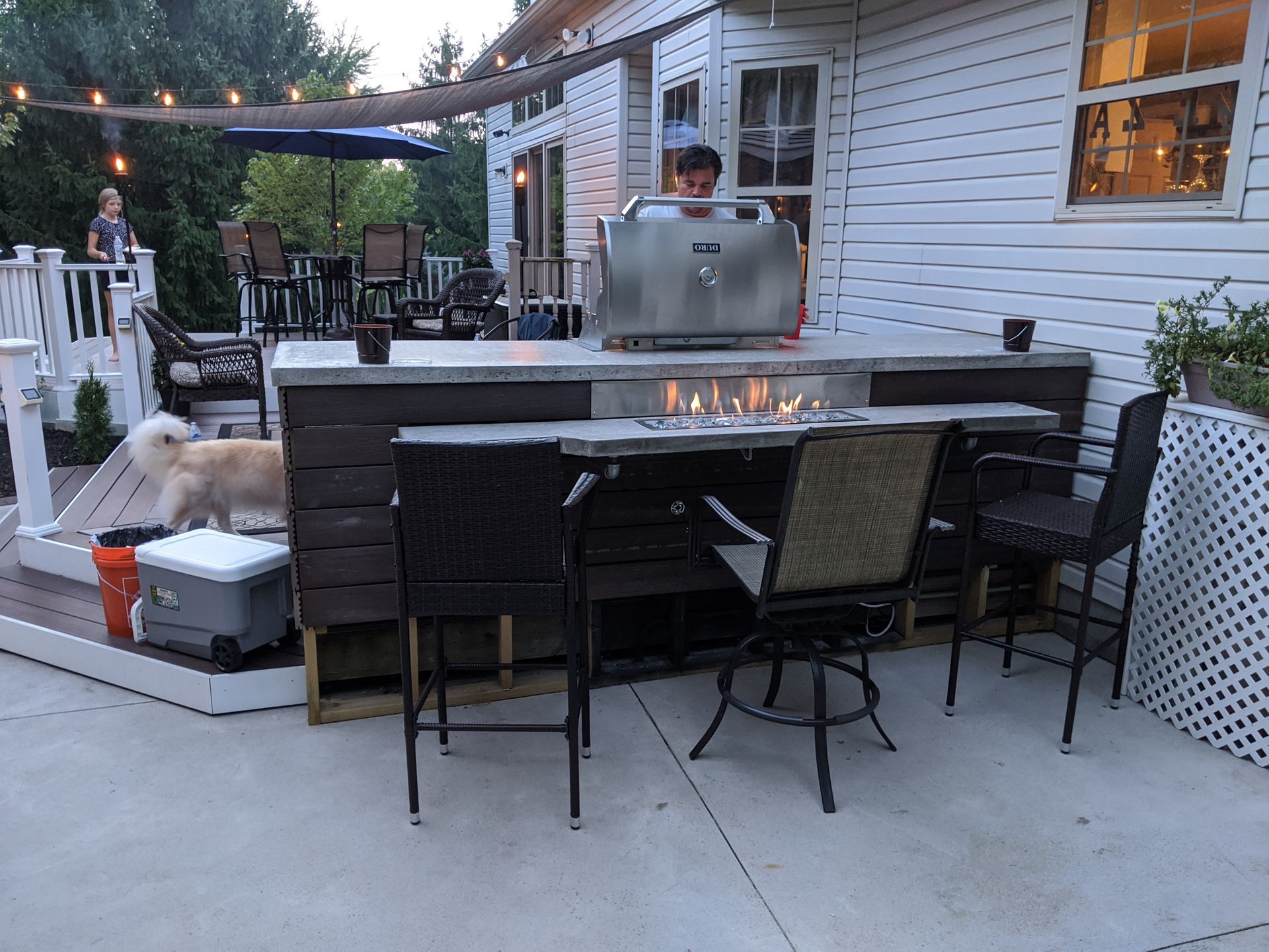 A man is standing behind a grill in a backyard