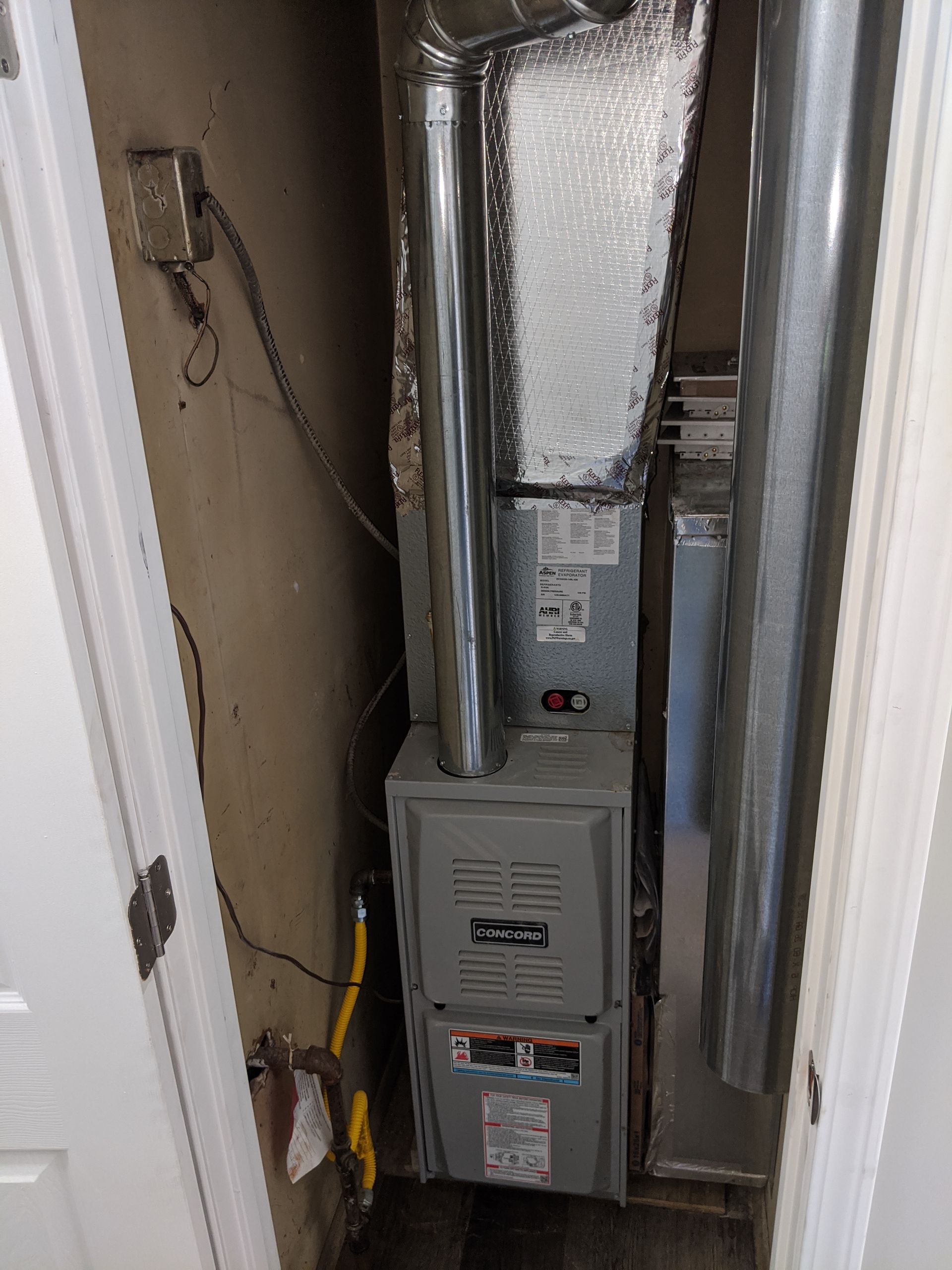 A furnace is sitting in a closet next to a door.