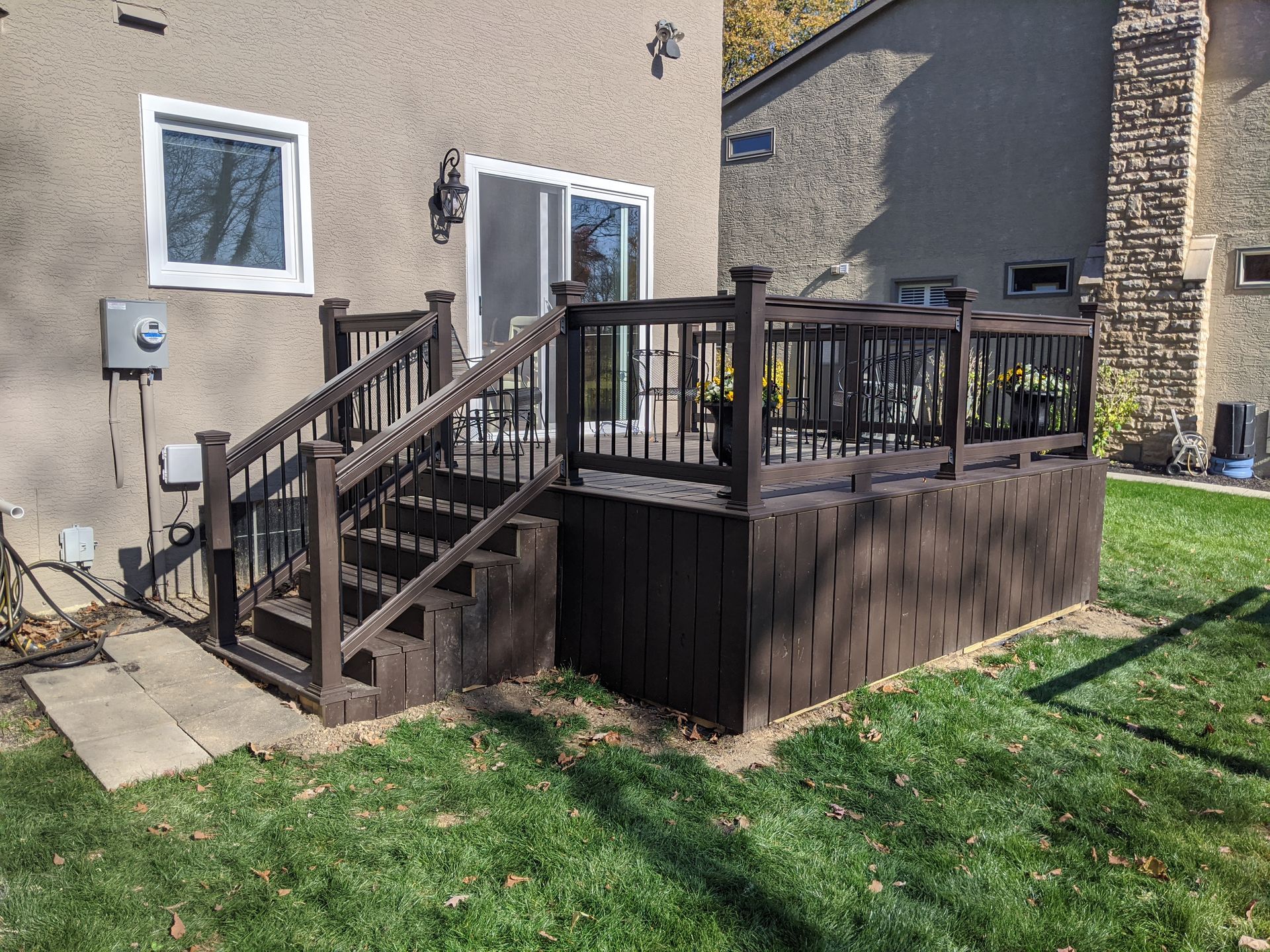 A wooden deck with stairs leading up to it is in the backyard of a house.