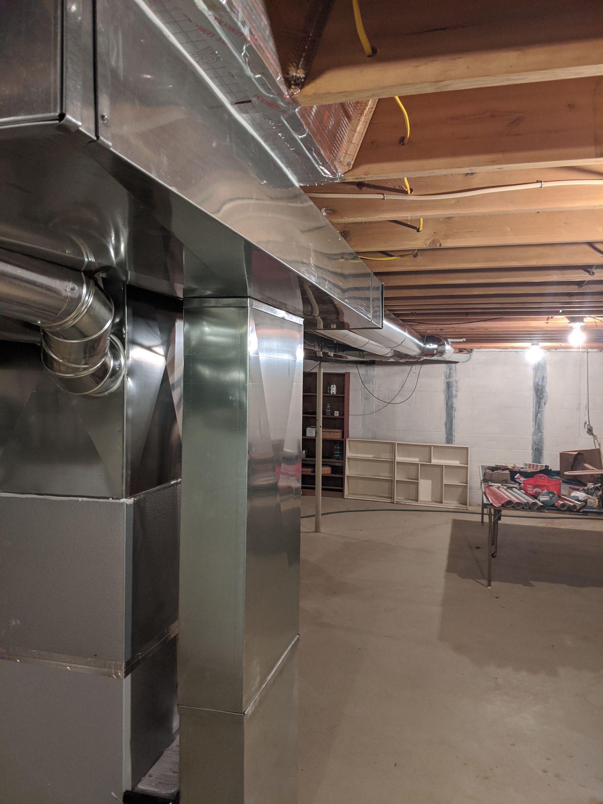 A basement with a metal wall and a wooden ceiling.
