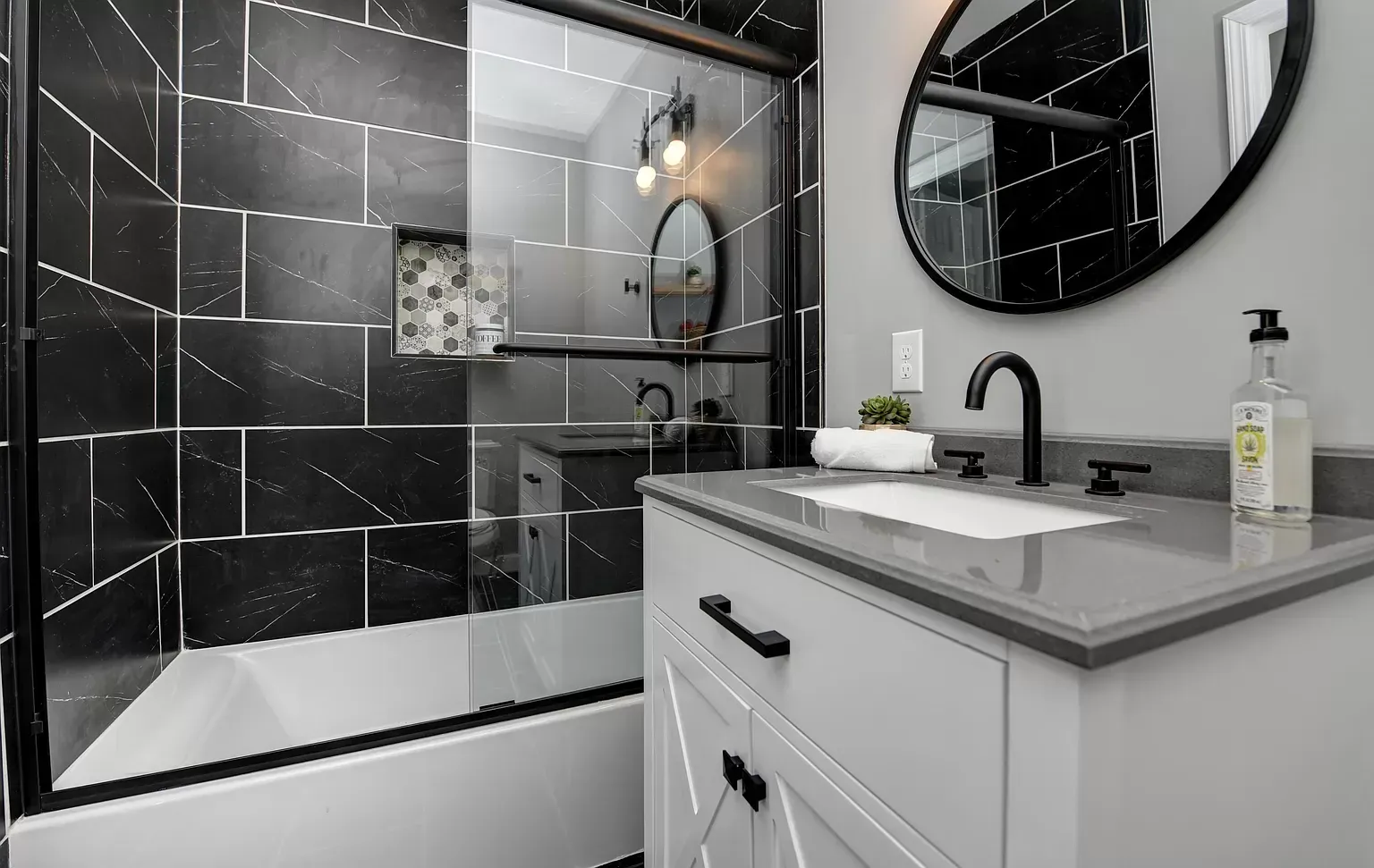 A bathroom with a sink , mirror , tub and shower.