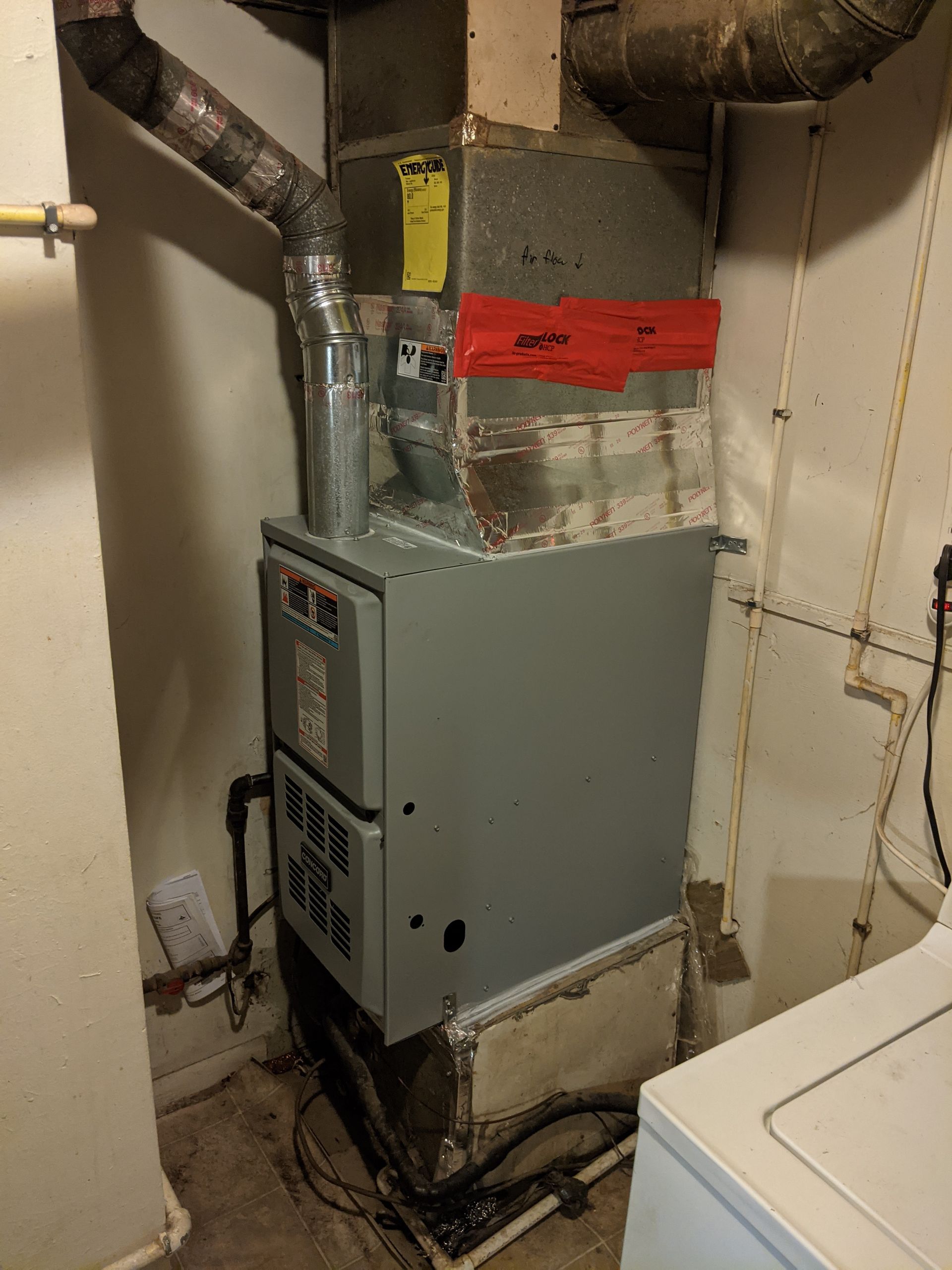 A furnace is sitting in a room next to a washer and dryer.