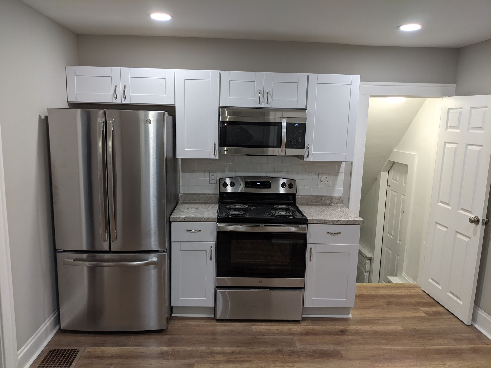 A kitchen with stainless steel appliances and white cabinets.