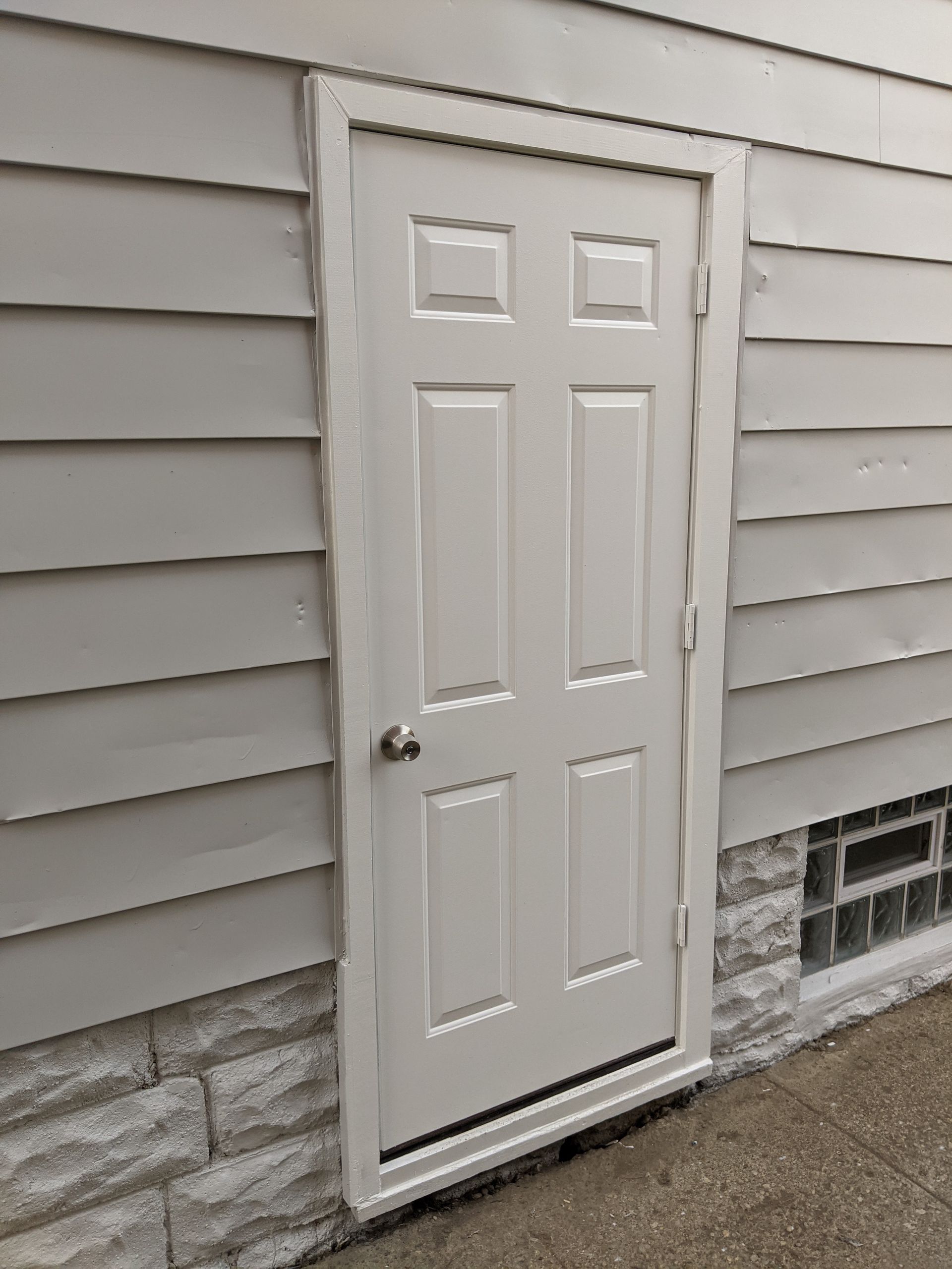 A white door is on the side of a house.