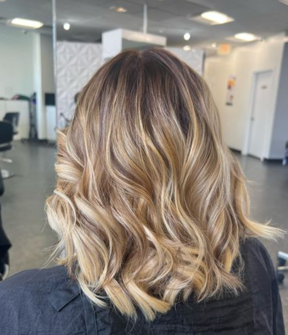A woman with blonde hair is sitting in a chair in a salon.