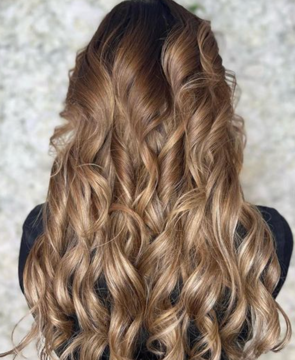 A woman with long curly hair is wearing a black shirt.