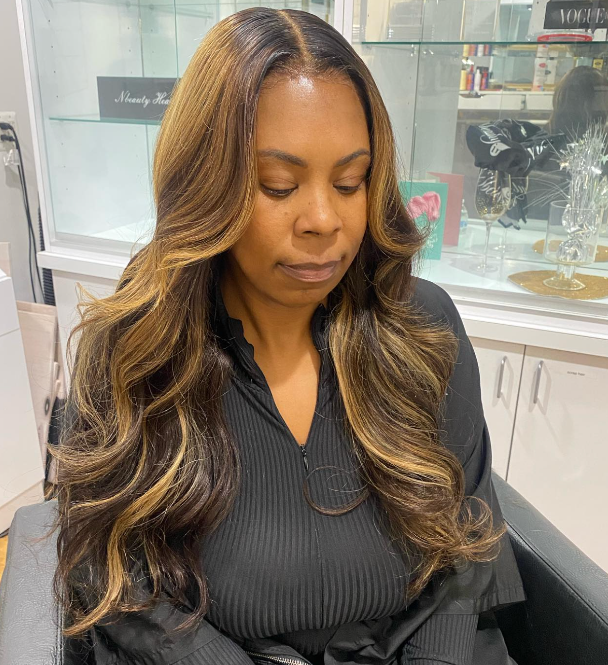 A woman with long hair is sitting in a chair with her eyes closed.