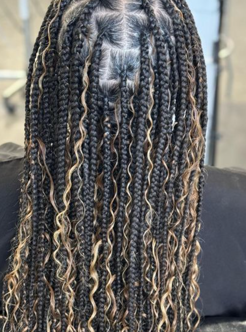 A woman with long braids and curly hair is wearing a wig.