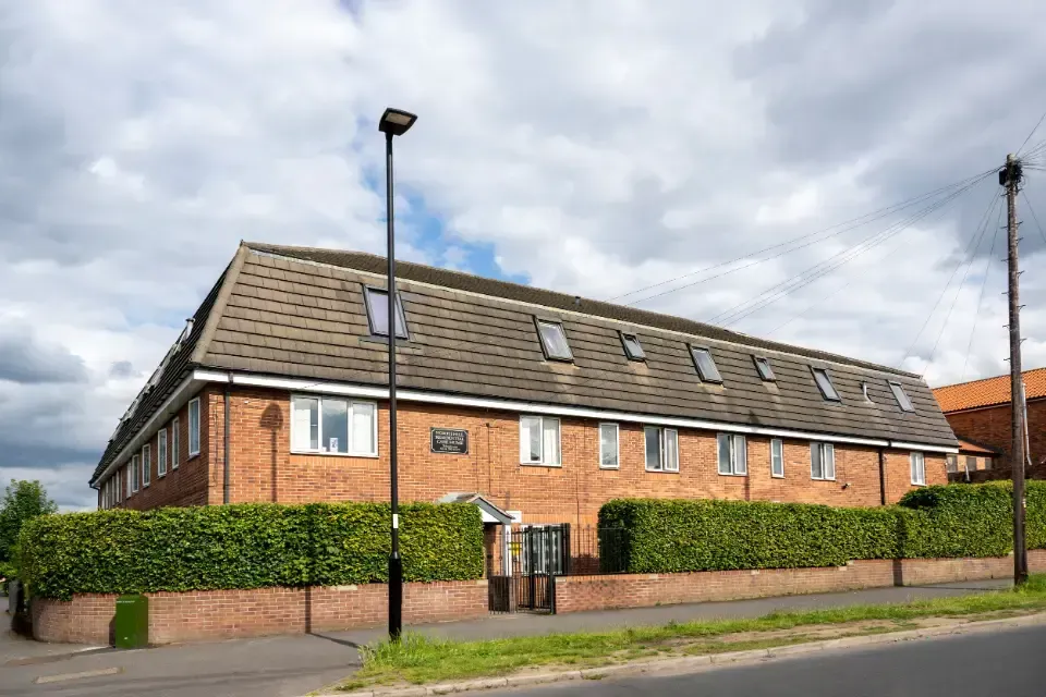 North Hill Residential Care Home, Southey Green, Sheffield | A large brick building with a roof that has a lot of windows and a street light in front of it.