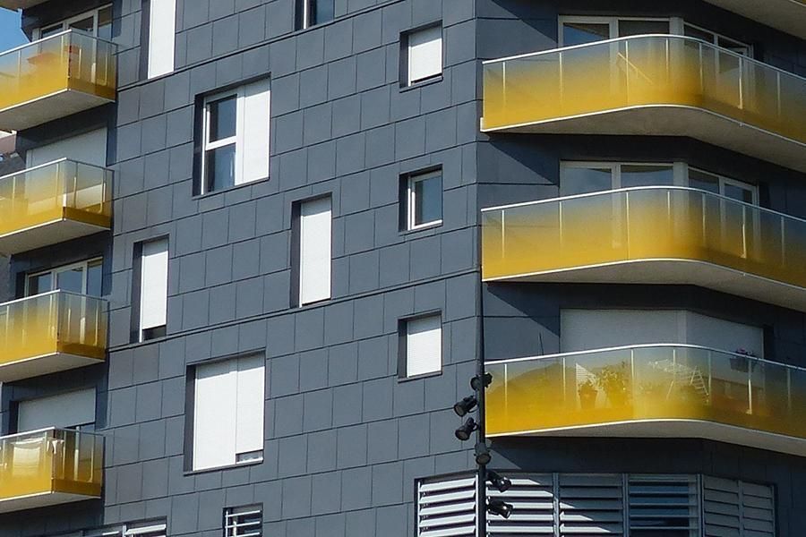Modern building exterior with gray facade and yellow balconies.