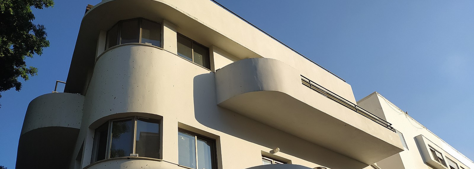 White Art Deco style building with curved elements against a clear blue sky.