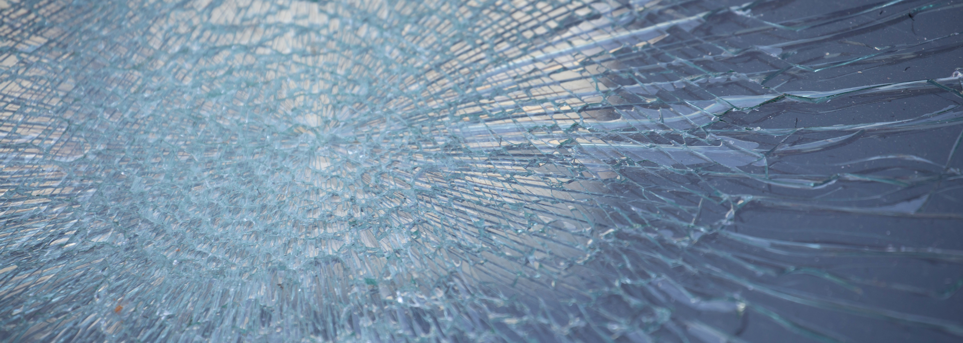 Shattered glass with radial cracks. The glass is primarily shades of blue and white, with a dark blue background.