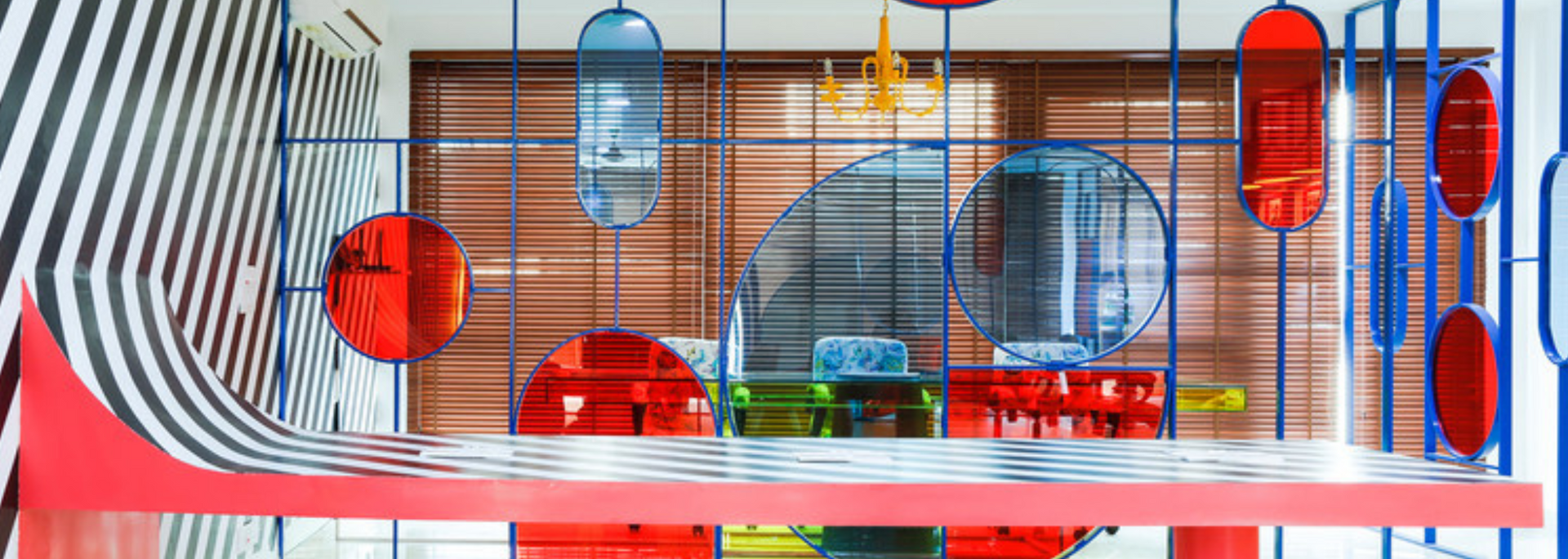 A colorful interior with red and blue accents, black and white striped wall, and hanging translucent decor.