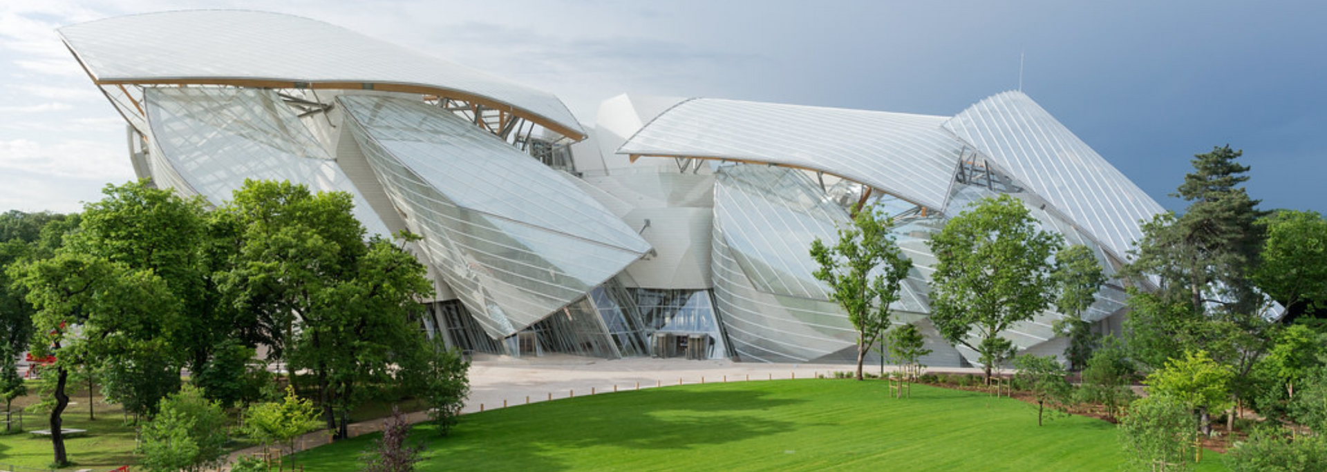 Exterior view of the Fondation Louis Vuitton, a modern art museum in Paris, France, with a striking glass facade.