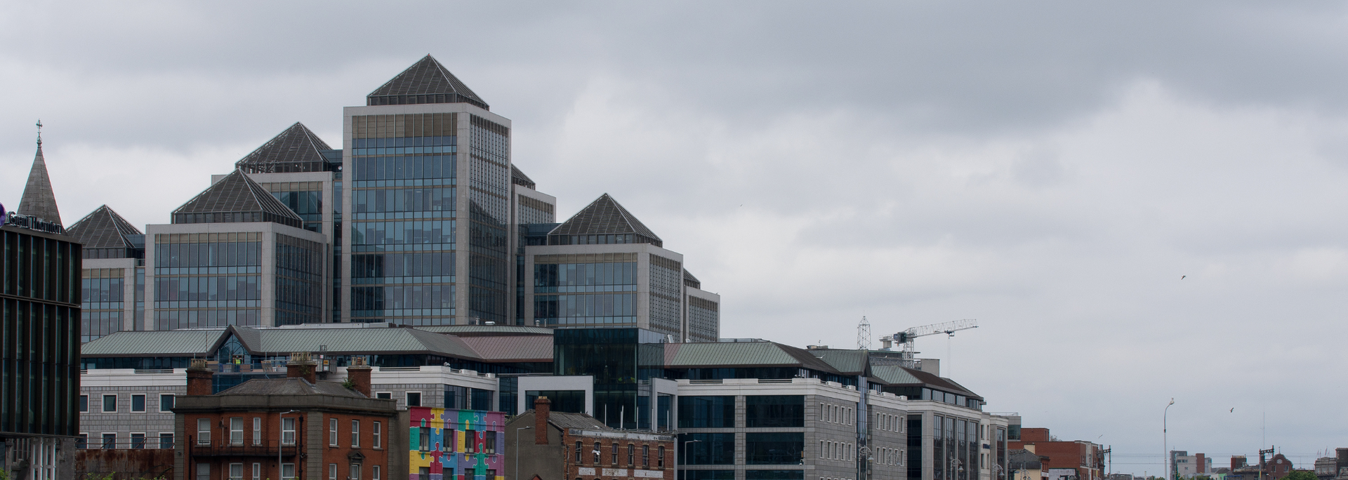 Buildings against an overcast sky. Modern glass building with pyramid-topped towers.