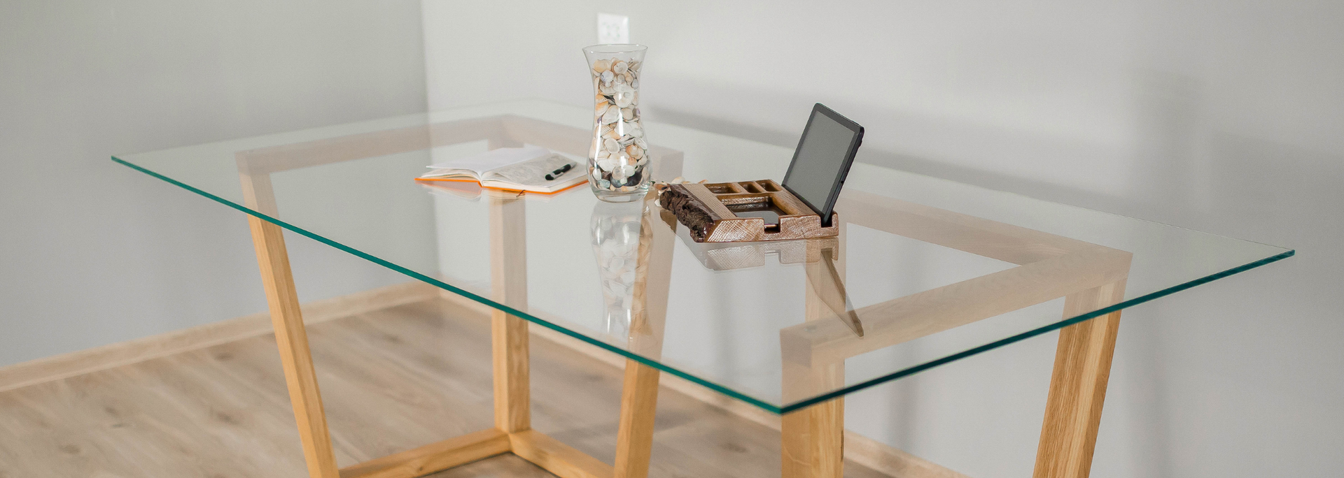 A glass-top table with wooden legs, topped with decorations and an open jewelry box.
