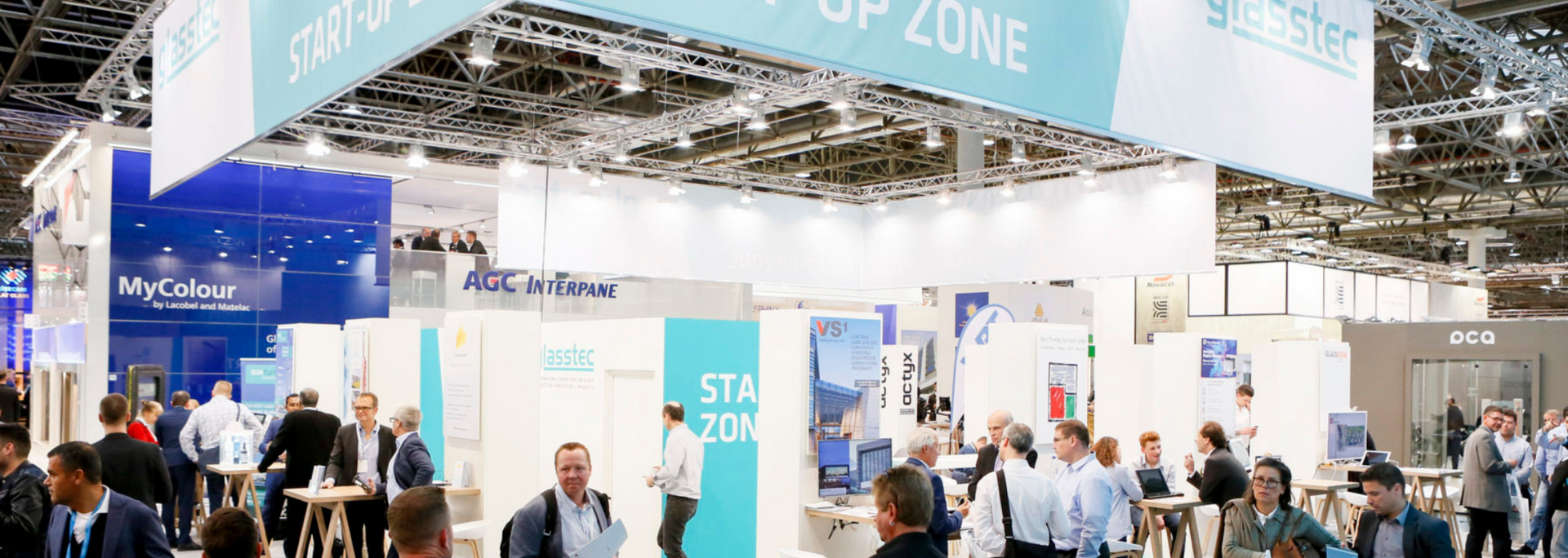 People at a trade show with booths, signs, and a suspended 