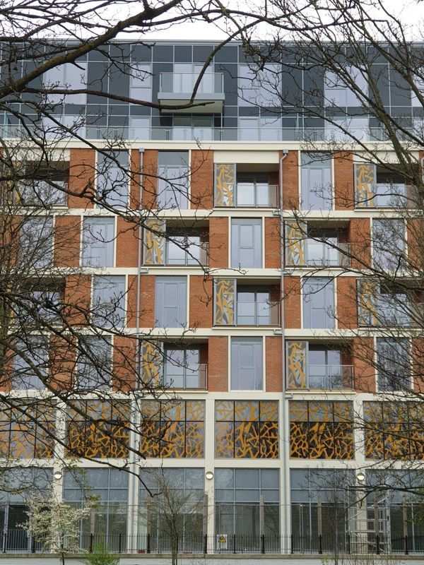 Modern brick and glass building with tree branches framing the view.