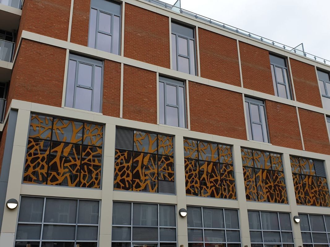 Brick building with multiple windows and decorative metal panels.