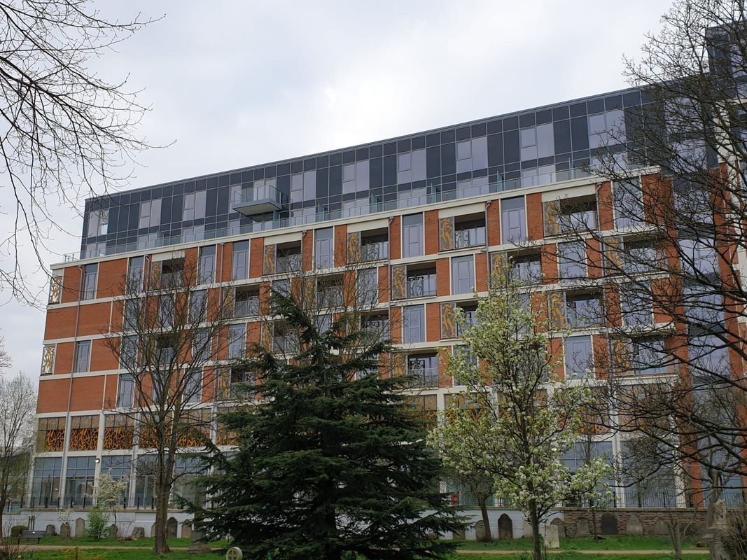 Multi-story building with orange and gray facade, trees in front.