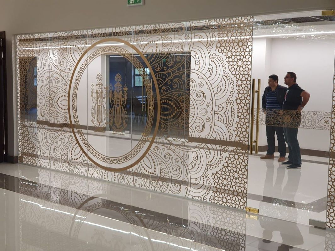 Ornate glass doorway with etched gold designs; two men standing inside.