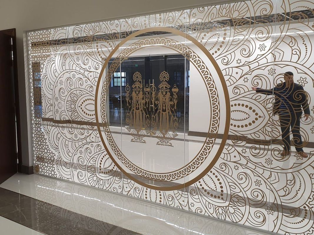 Decorative wall with a circular design, person on the right posing, building interior.