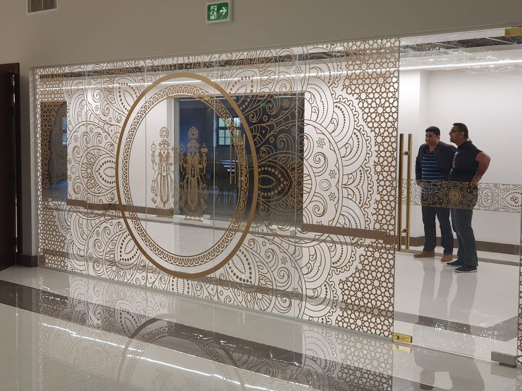 Ornate glass entrance with gold designs; two men stand in doorway.