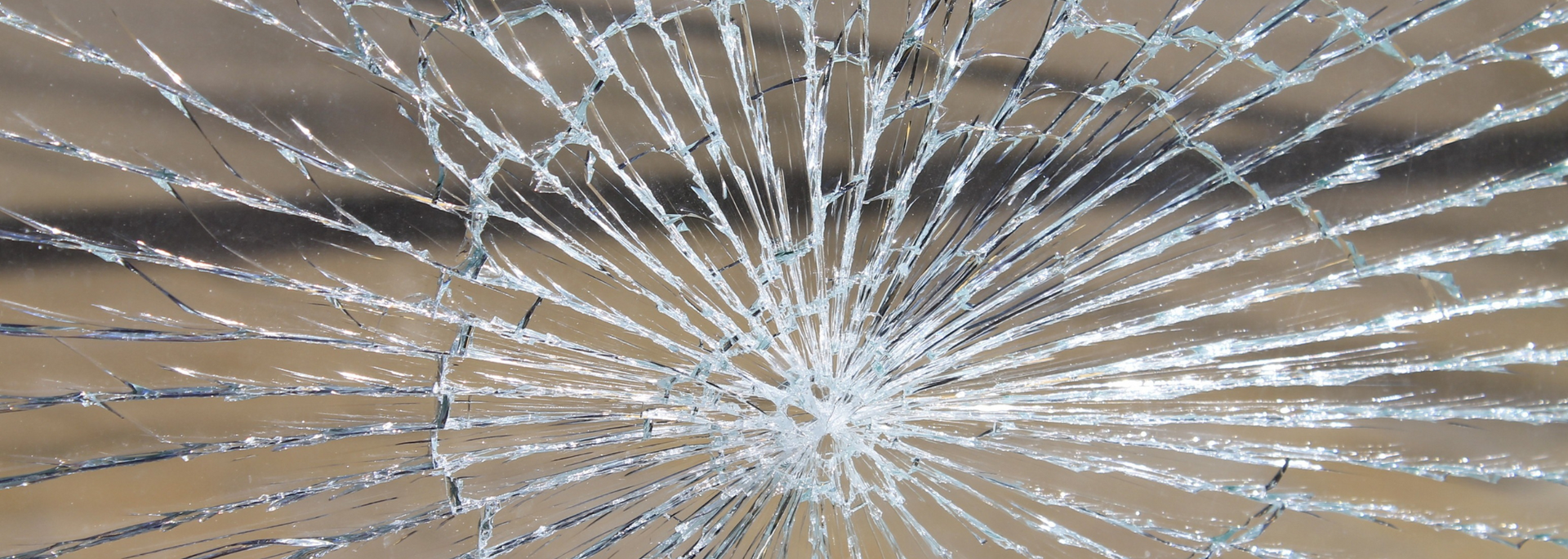 Cracked glass with a radial pattern against a light brown background.
