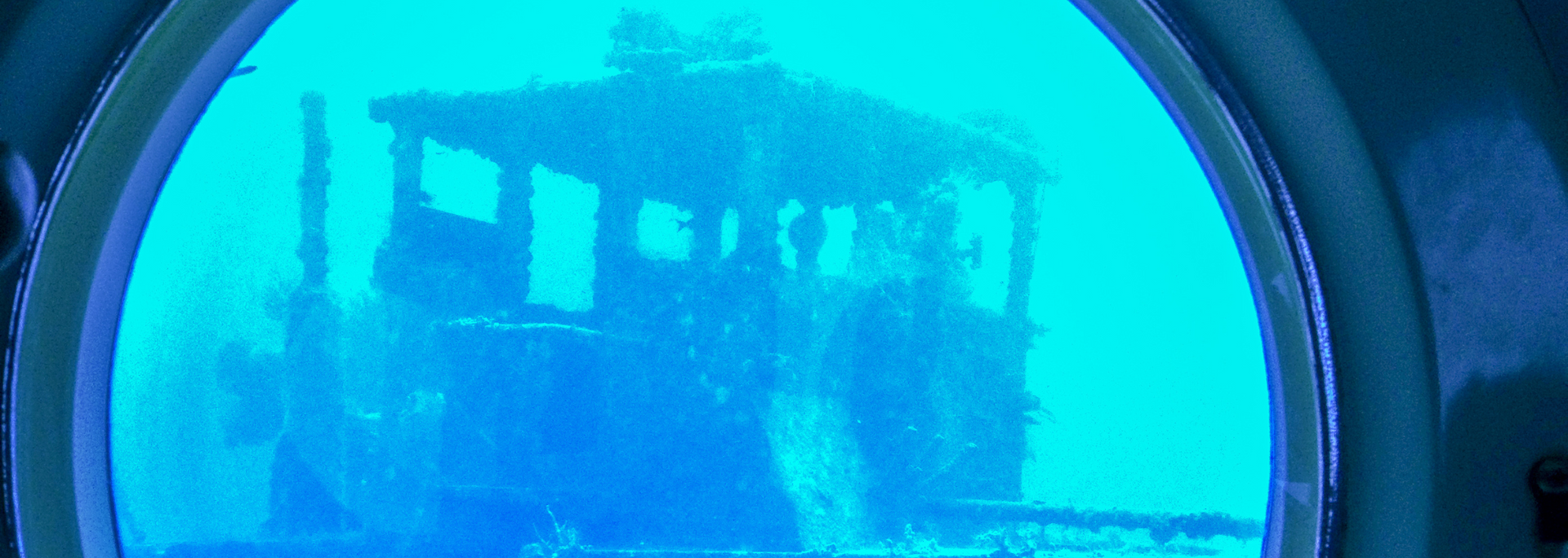 View from a submarine porthole of a train submerged underwater.