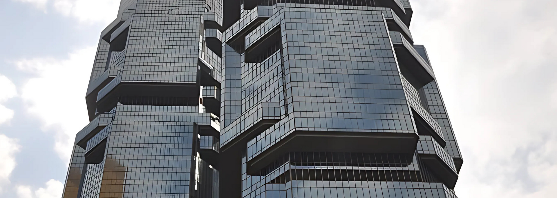 A modern glass skyscraper against a cloudy sky.