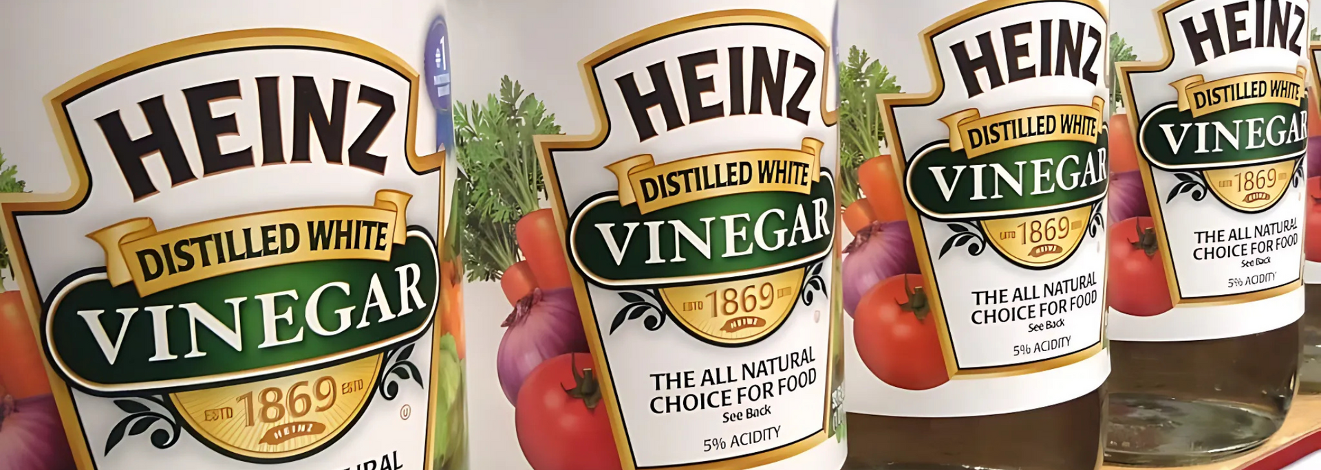 Close-up of several Heinz distilled white vinegar bottles in a row, with labels visible.