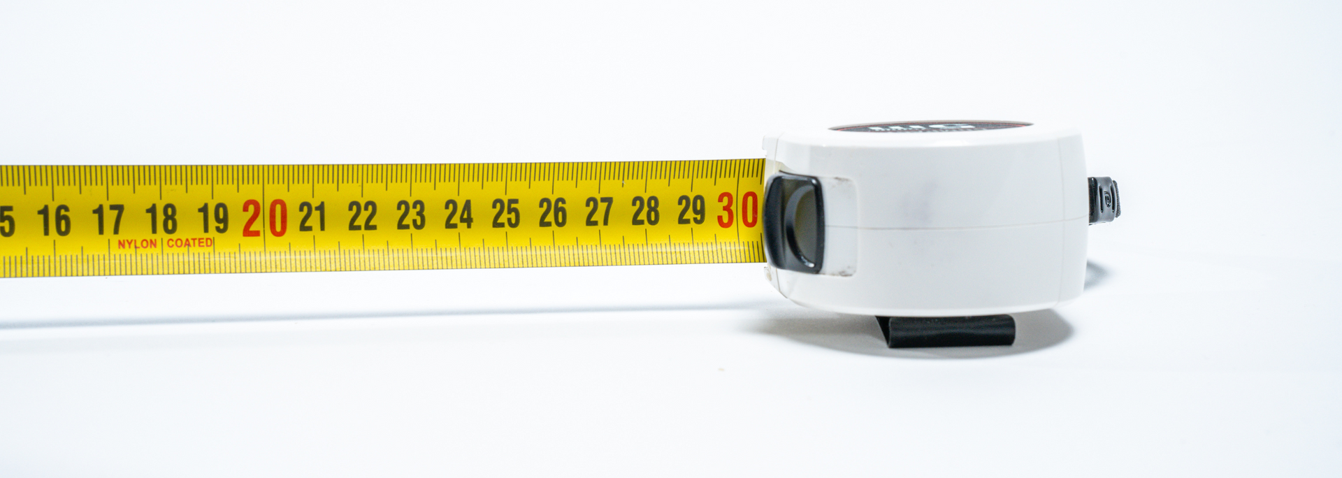 A yellow tape measure, extended to 30 inches, rests on a white background.