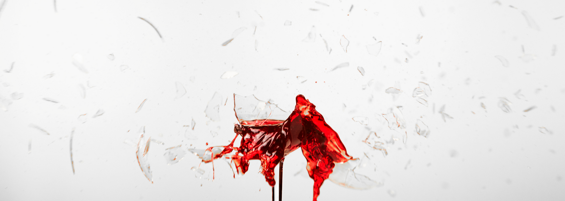 A glass with blood spilling out against a white background.