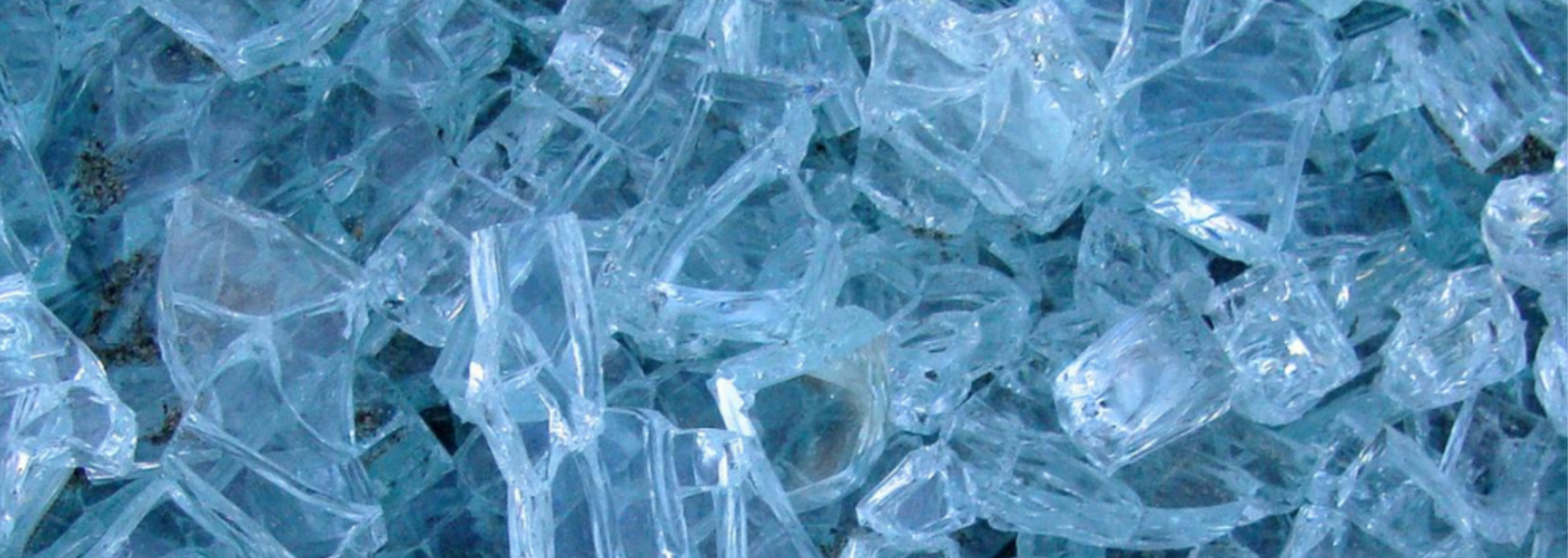 Close-up of broken glass pieces, primarily blue and clear, creating a jagged, textured surface.