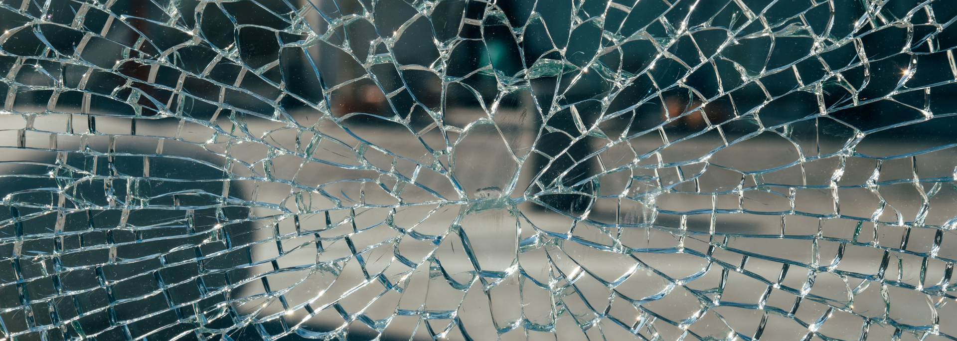 Cracked glass pane with the blurred image of a person standing outside.
