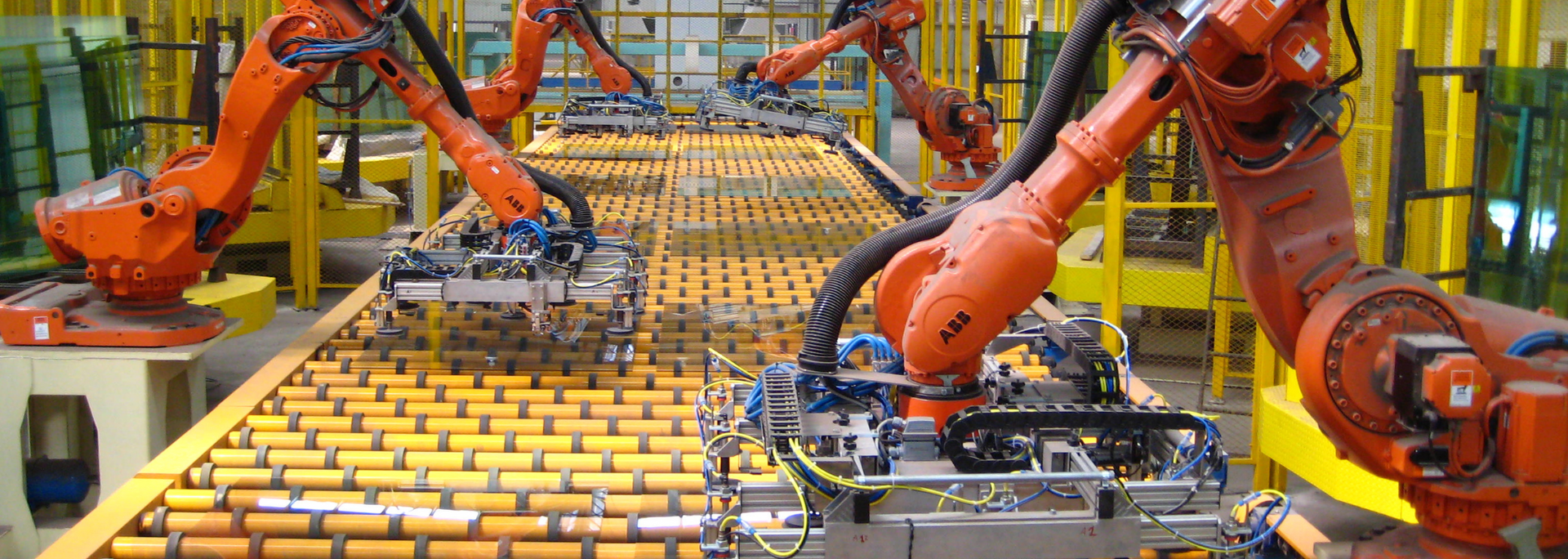 Orange robotic arms on an assembly line with yellow and silver elements.