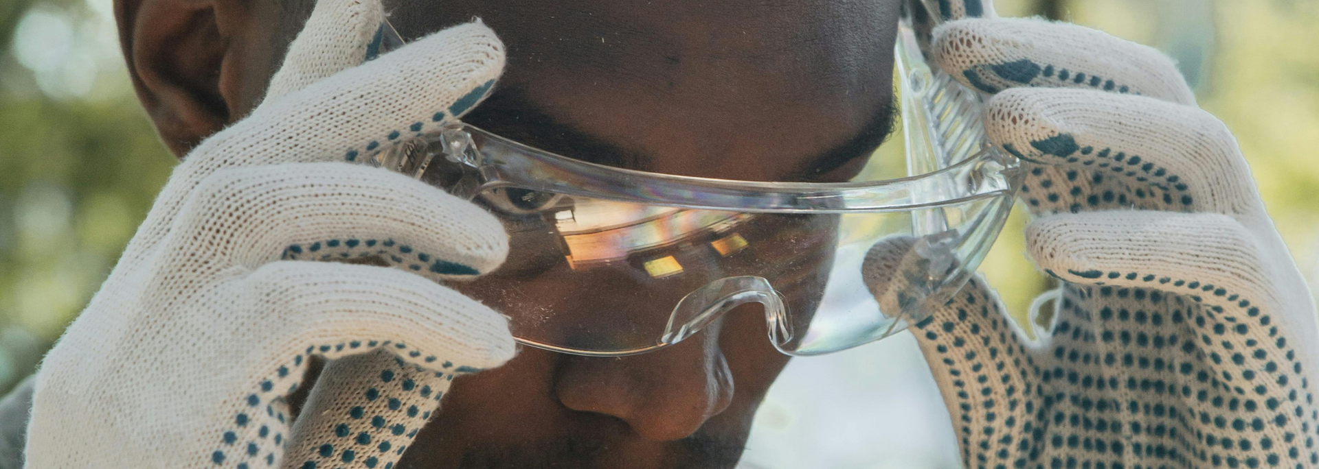Person wearing gloves puts on safety glasses.