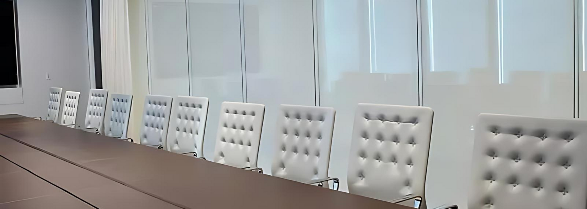 Conference room with a long table and white tufted chairs.