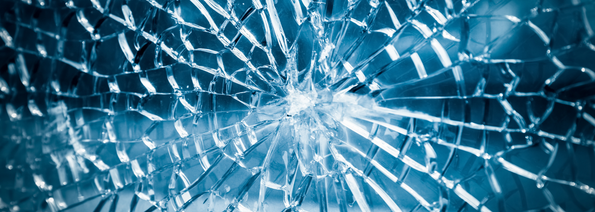 Broken glass with a blue hue, radiating outward from a central point.