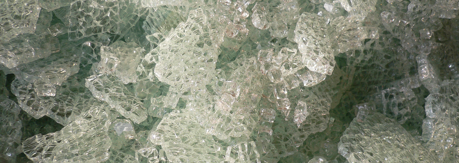 Close-up of clear, jagged glass shards with a slightly green tint.