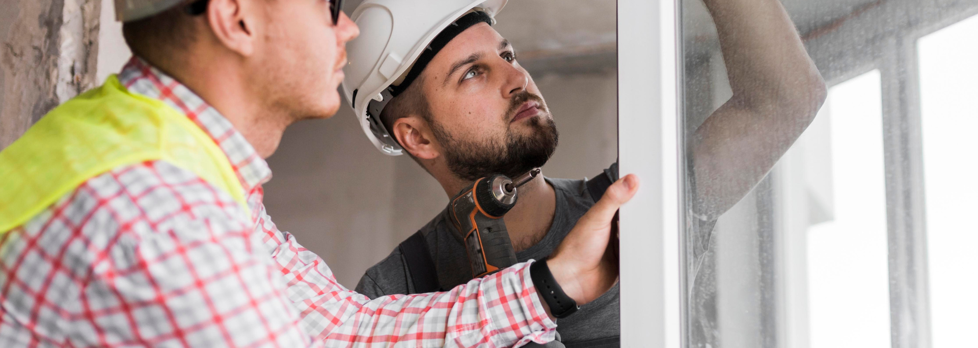 Two construction workers examining a white door frame indoors.