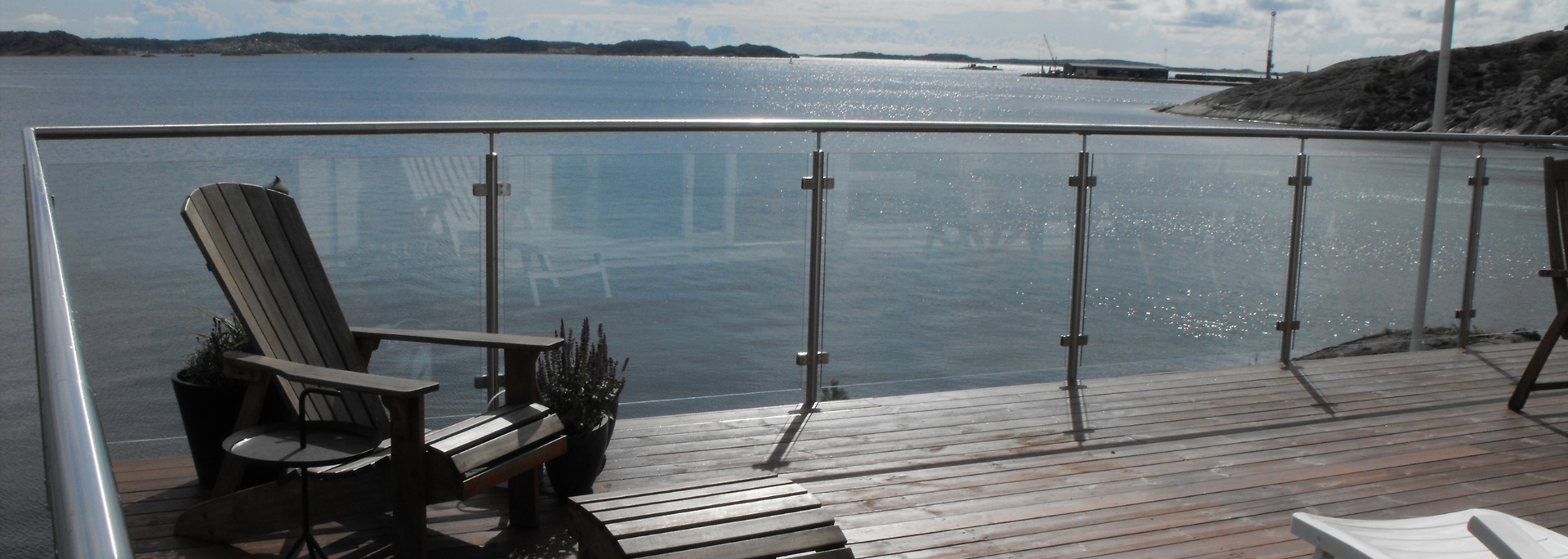 Wooden chair on a deck overlooking a body of water with a bridge in the distance.