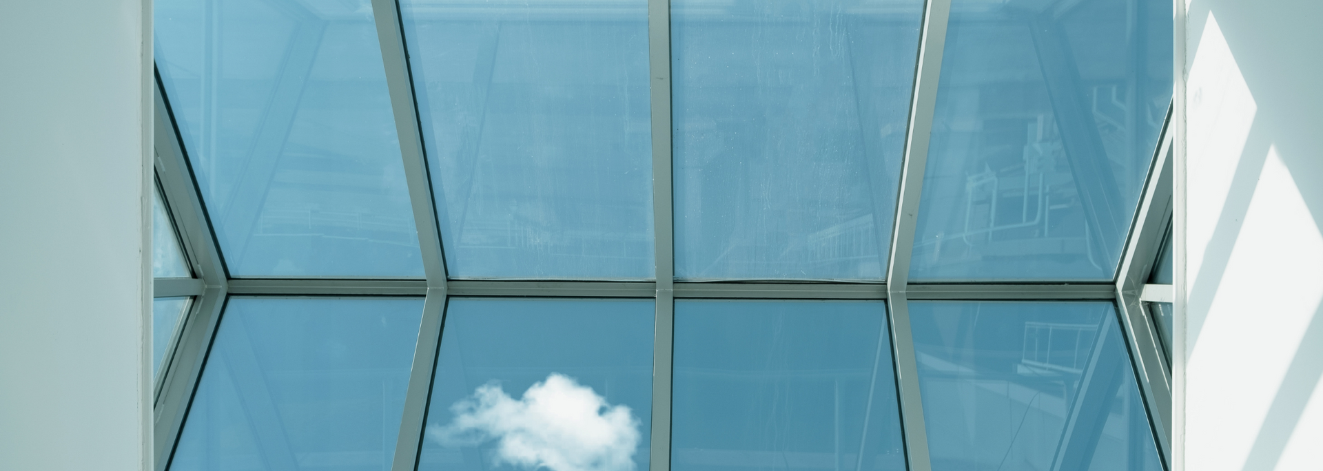 Skylight in a building. Clear blue sky with a few clouds seen through the glass panels.