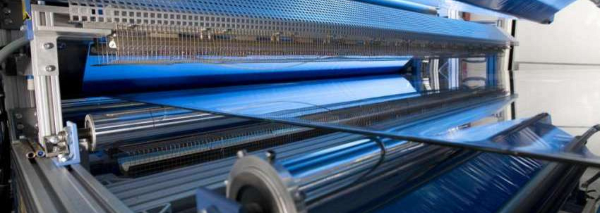 Blue plastic sheet being processed by an industrial machine.
