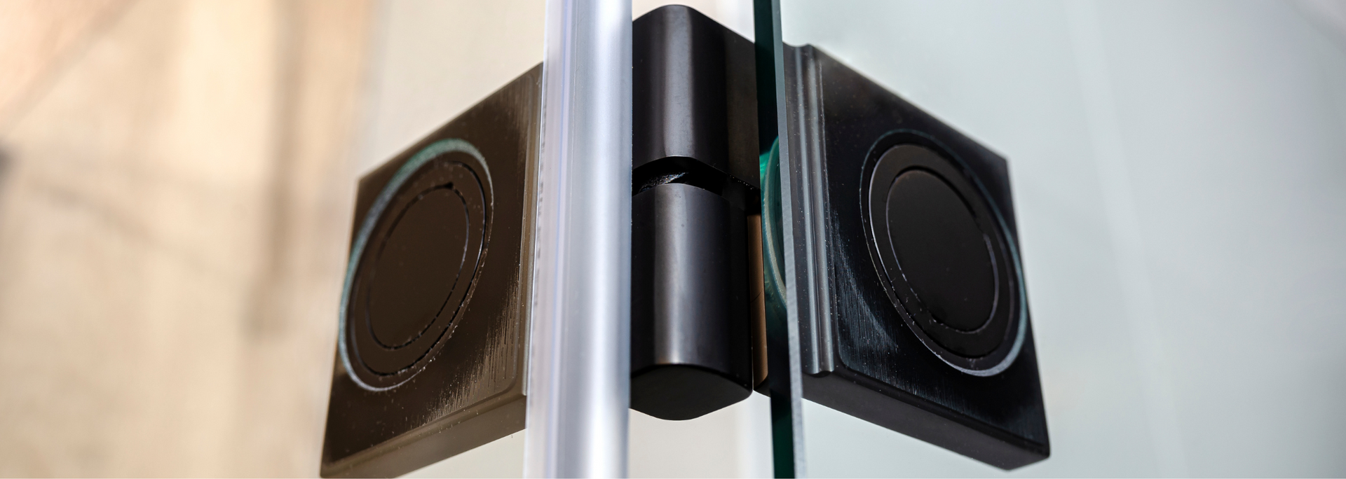 Black door hinge connecting glass panels.