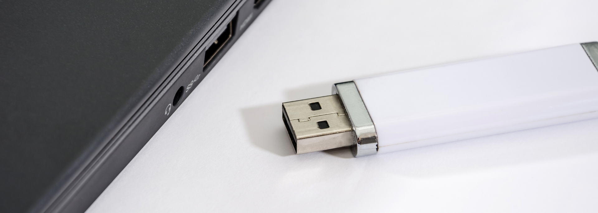 White USB drive plugged into a laptop.